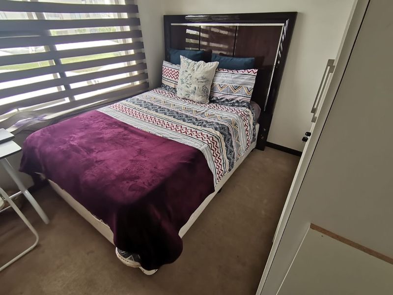 A compact bedroom featuring a built-in wardrobe and venetian blinds, providing a functional and private sleeping space.
