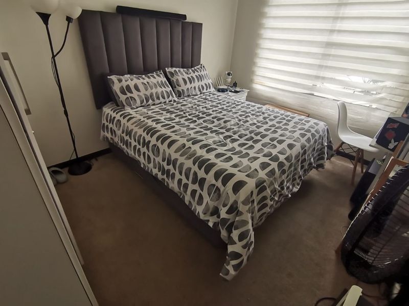 A functional bedroom featuring neutral wall finishes, carpeted flooring, and integrated roller blinds for privacy.