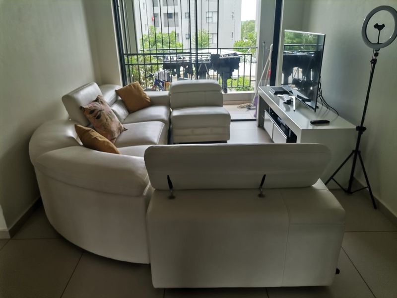 A living room area featuring tiled flooring and a sliding glass door providing access to a balcony with security gate.