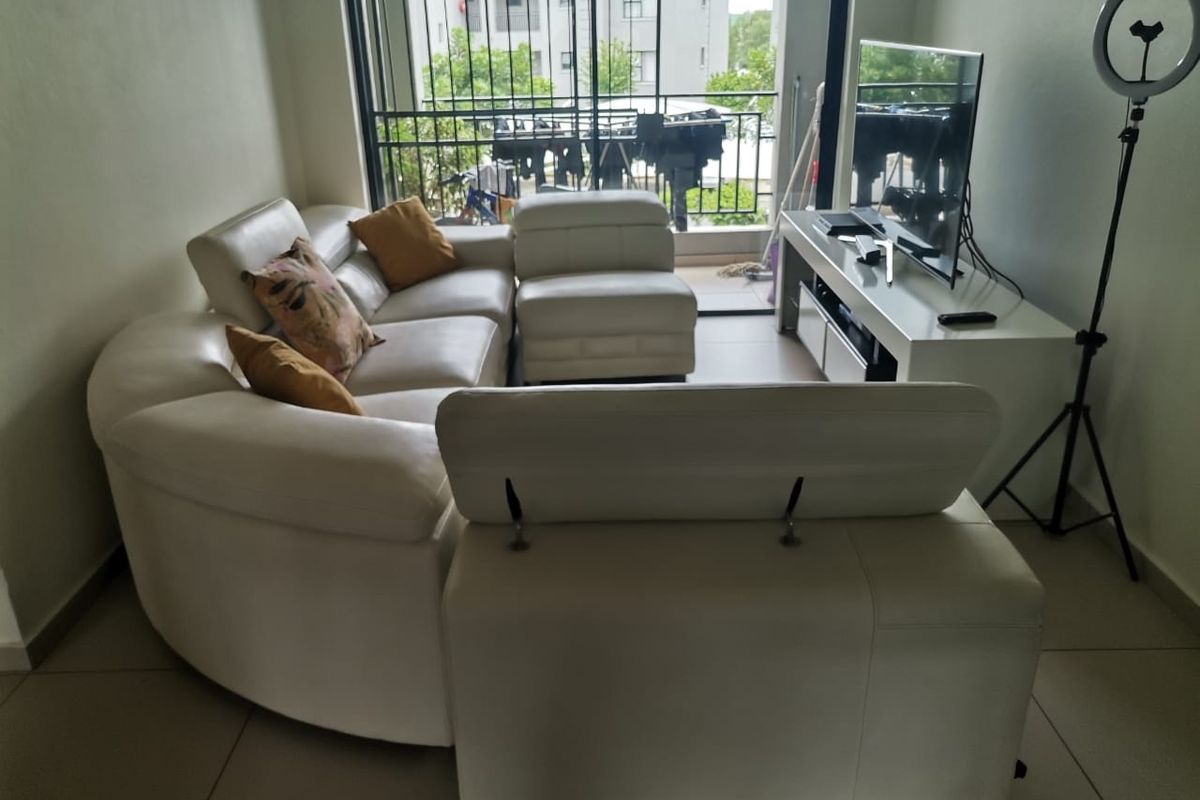 A living room area featuring tiled flooring and a sliding glass door providing access to a balcony with security gate.