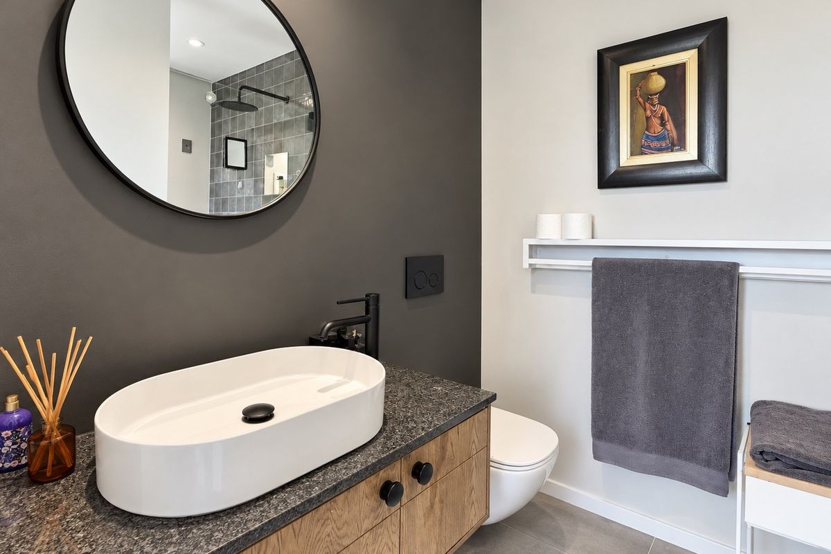 Modern bathroom featuring a wood vanity with stone countertop, vessel sink, wall-mounted toilet, and a sleek walk-in shower with grey tiling.