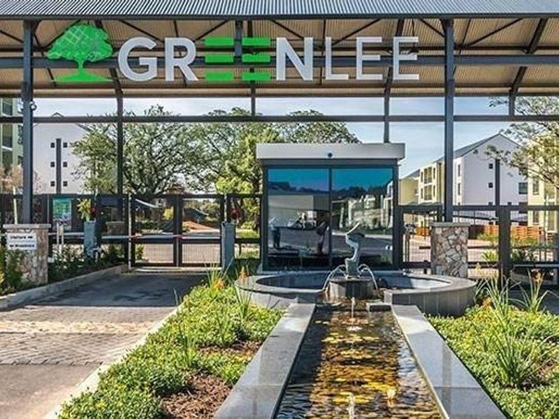 The secure entrance to Greenlee apartment complex featuring a modern gatehouse, boom gates, and a landscaped water feature.