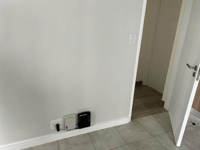 A clean, neutral-toned hallway featuring tiled flooring, modern skirting boards, and an internal door leading to an adjacent room.