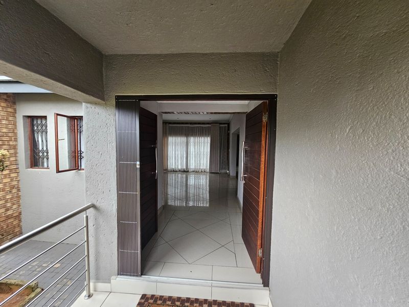 Entrance area featuring double timber doors leading into a tiled interior space with a view through to the living area.