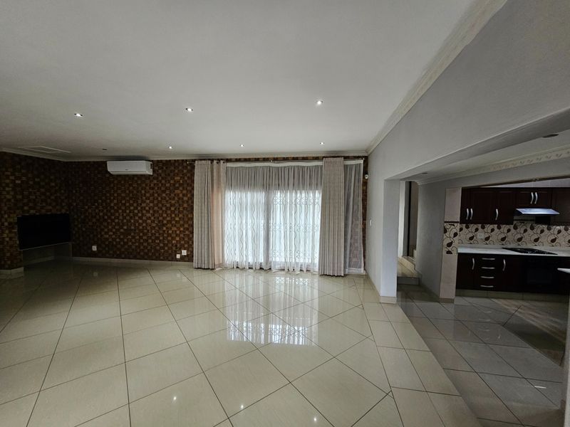 Spacious open-plan living area featuring polished tile flooring, recessed lighting, and a modern kitchen with built-in cabinetry and appliances.