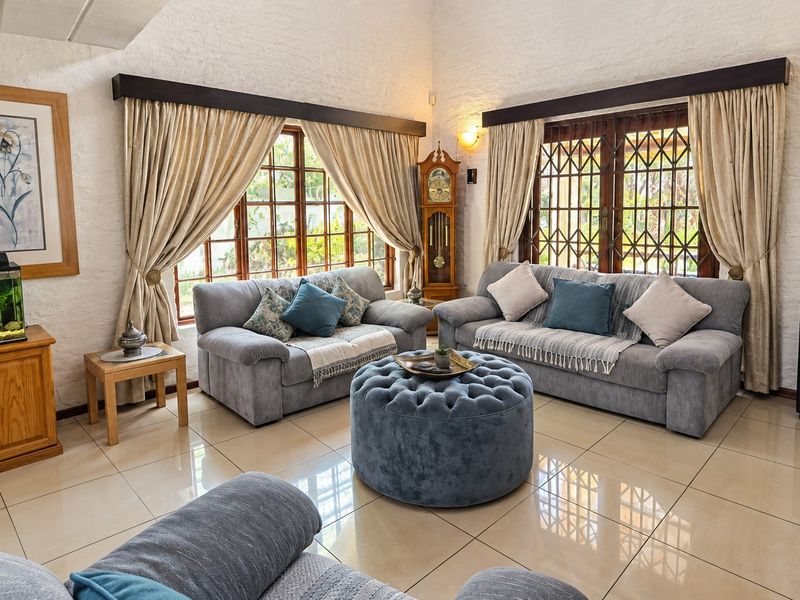 Spacious living room featuring large windows with security gates, tiled flooring, and textured walls, offering a bright and comfortable atmosphere.