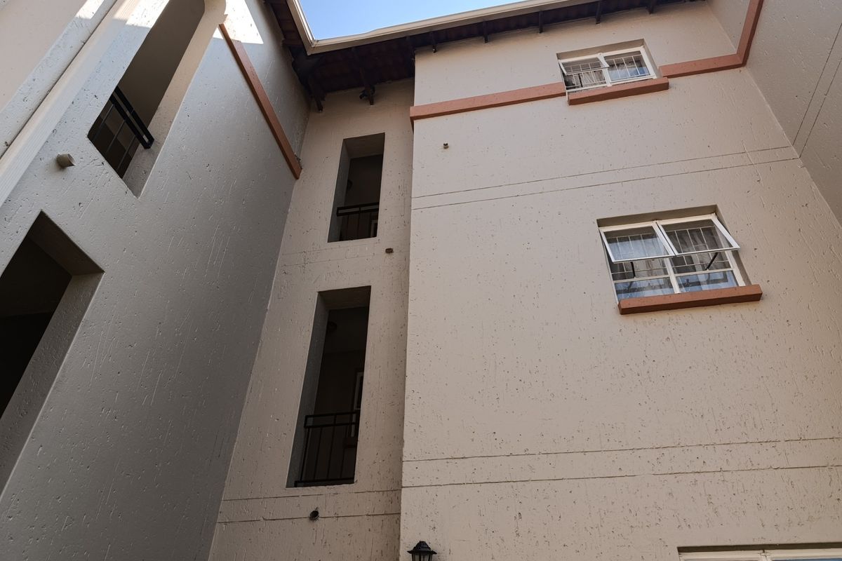 Low angle view of the apartment building exterior showing textured facade, multiple window levels, and balcony access points.