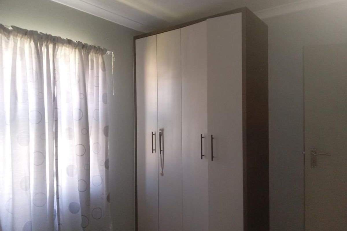A bedroom featuring a neutral color palette, a built-in wardrobe with modern handles, and decorative cove cornicing.