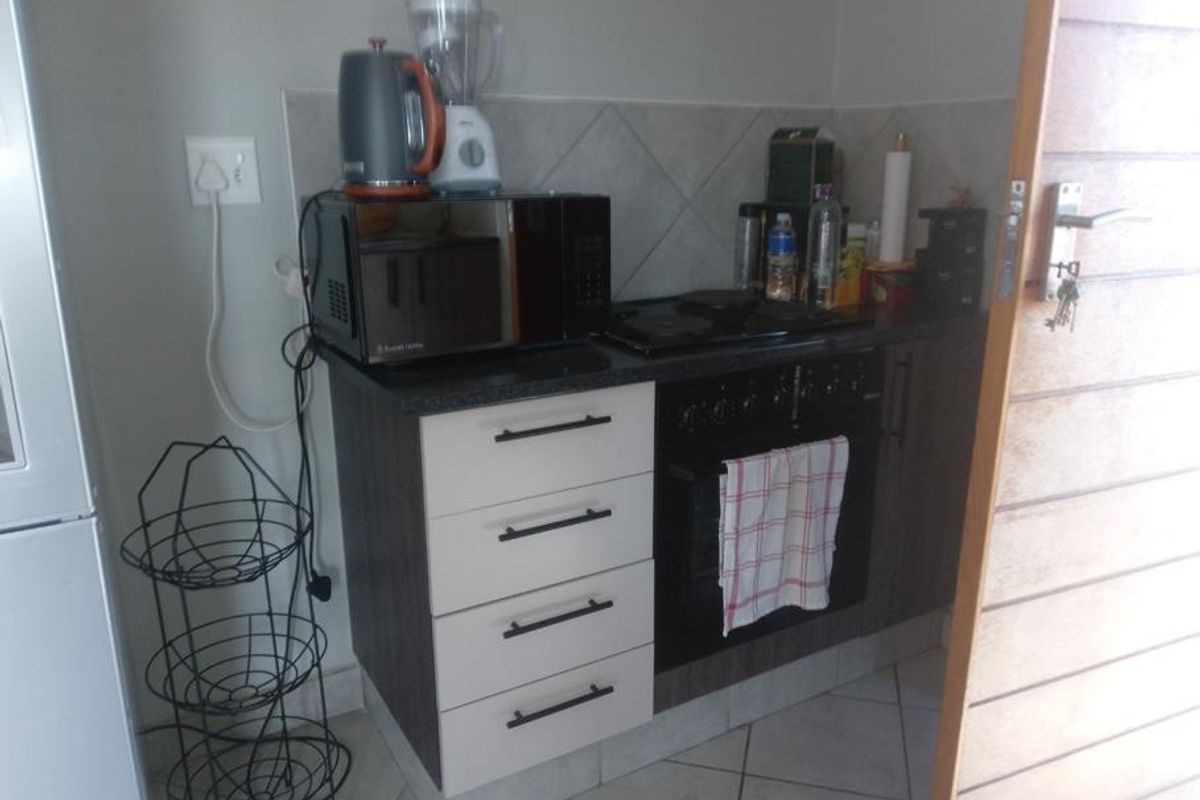 A compact kitchen area featuring built-in cabinetry, a hob, an oven, and tiled backsplash, providing essential cooking functionality in a small footprint.