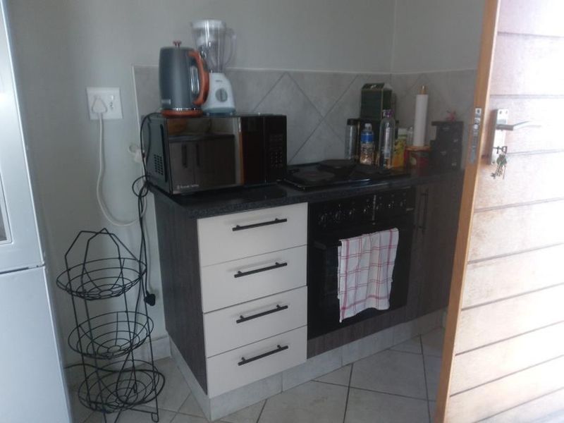 A compact kitchen area featuring built-in cabinetry, a hob, an oven, and tiled backsplash, providing essential cooking functionality in a small footprint.