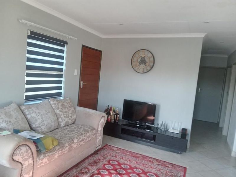 A well-maintained living room featuring neutral wall tones, tiled flooring, and modern roller blinds, providing a comfortable and functional space.