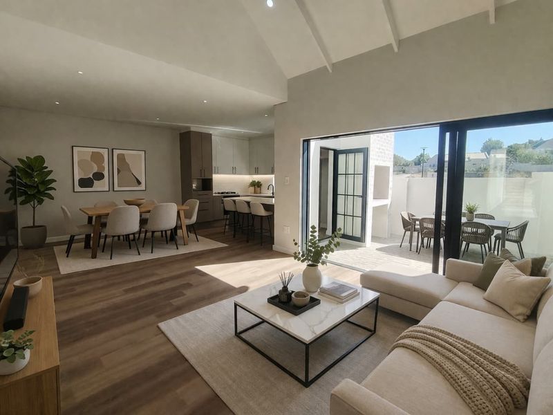 Spacious open-plan living area featuring vaulted ceilings, modern kitchen with island, and seamless flow to a private outdoor patio with built-in braai.