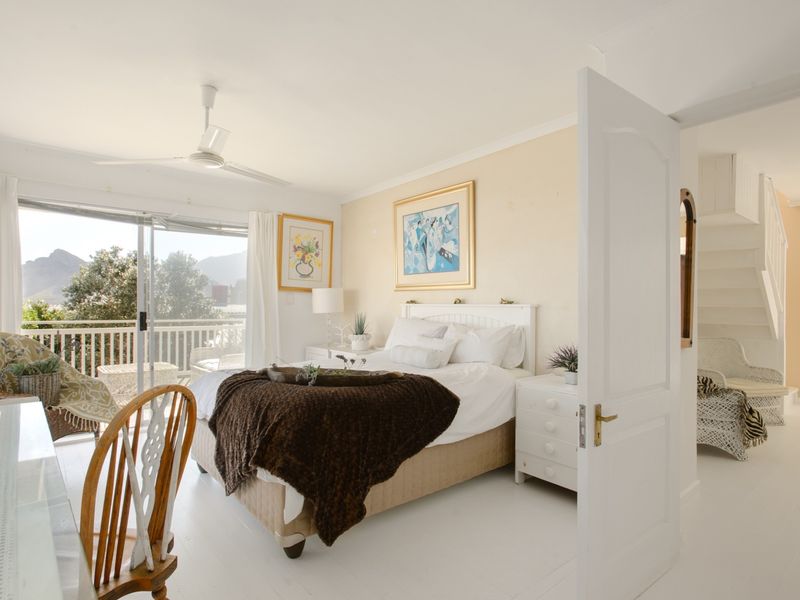 Bright bedroom featuring a ceiling fan, sliding glass doors leading to a balcony, and an adjacent staircase.