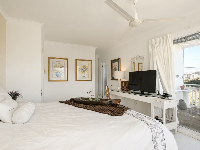 A bright bedroom featuring a ceiling fan and direct access to an outdoor balcony through sliding glass doors.
