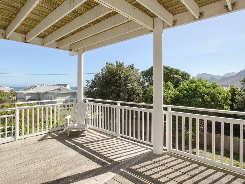 Spacious elevated timber balcony featuring a pergola, white balustrade railing, and scenic views of the surrounding landscape and mountains.