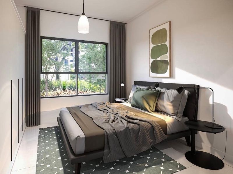 A modern, well-lit bedroom featuring built-in wardrobes, tiled flooring, and a large window overlooking greenery.