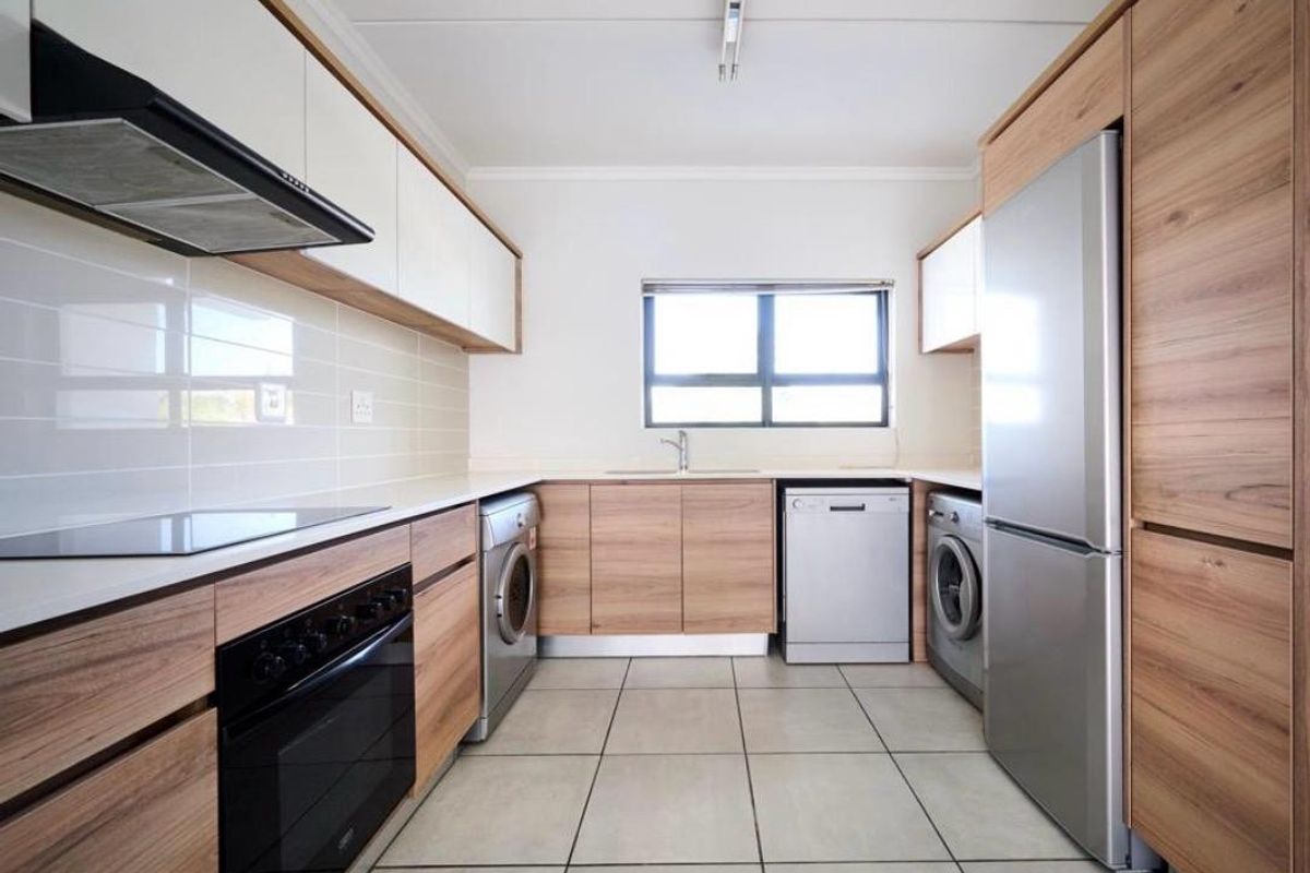 Modern kitchen featuring wood-grain cabinetry, white countertops, tiled flooring, and integrated appliance spaces, offering a clean and functional layout.
