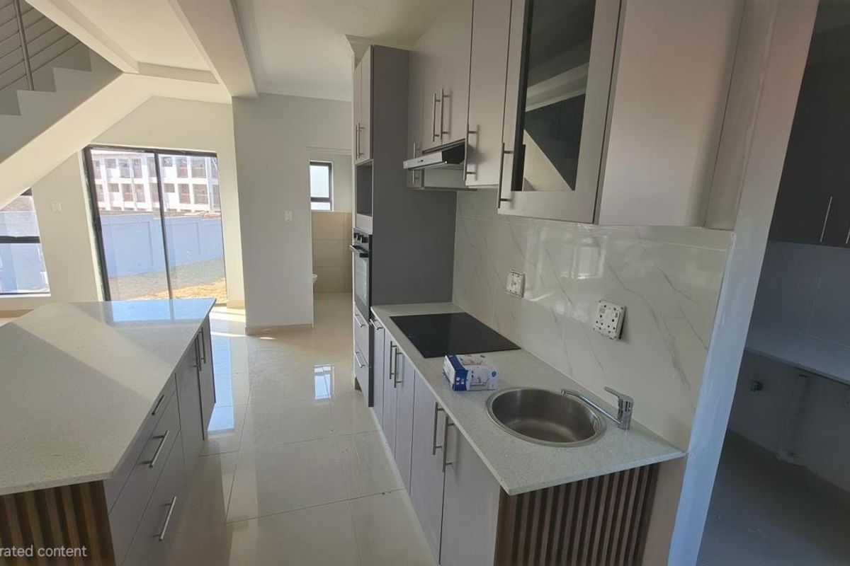 Modern kitchen featuring a central island, stone countertops, built-in cabinetry, integrated appliances, and a marble-look splashback, adjacent to an open-plan living area.
