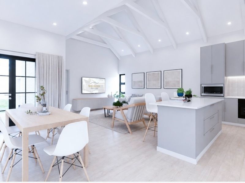 Modern open-plan living area featuring a vaulted ceiling with exposed rafters, a contemporary kitchen with an island, and direct access to the outdoors.