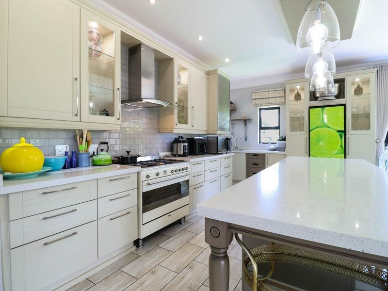 Modern kitchen featuring cream cabinetry, stone countertops, a large central island, gas stove with extractor, and stylish subway tile backsplash.