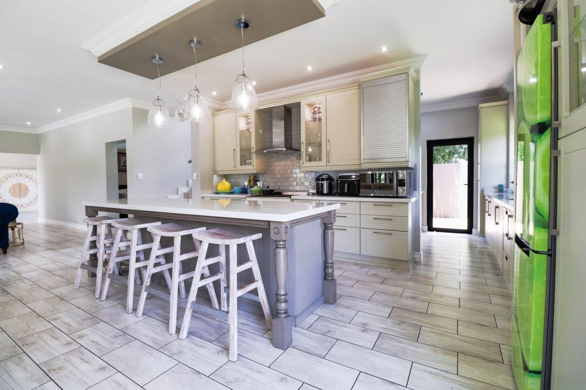 Modern kitchen featuring a central island with stone countertops, ample built-in cabinetry, subway tile backsplash, and stylish pendant lighting over the breakfast bar area.