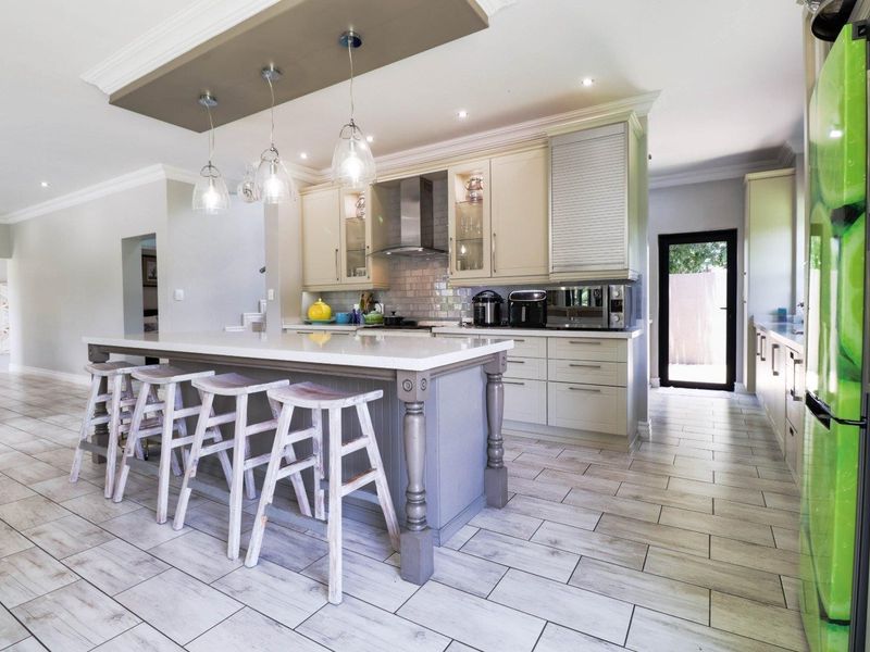 Modern kitchen featuring a central island with stone countertops, ample built-in cabinetry, subway tile backsplash, and stylish pendant lighting over the breakfast bar area.