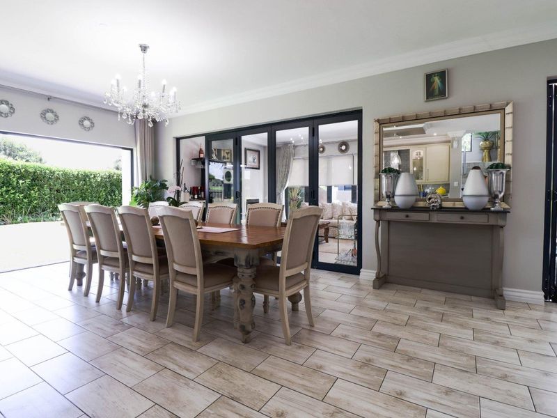 Spacious dining room featuring elegant tiled flooring, a crystal chandelier, and large bi-fold doors providing seamless access to the outdoor patio area.