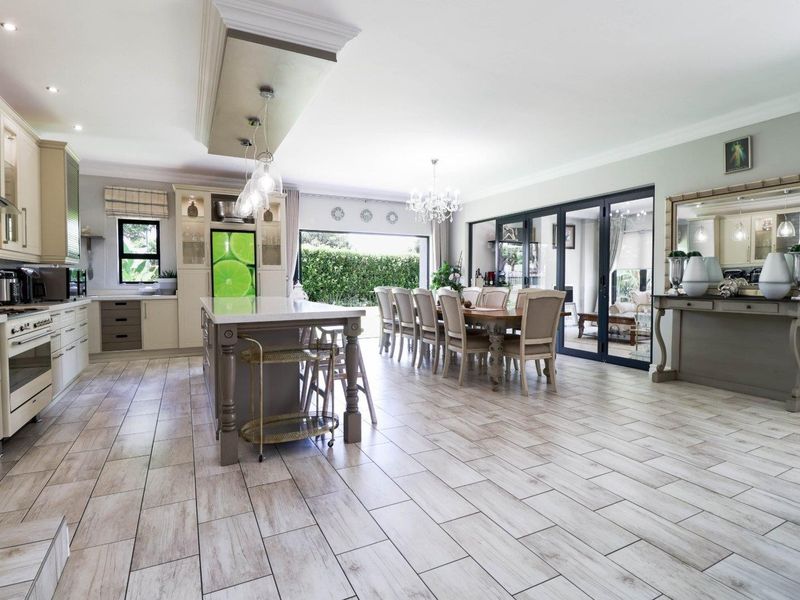 Spacious open-plan kitchen and dining area featuring a large island, modern cabinetry, tiled flooring, and seamless access to the outdoor patio through sliding doors.