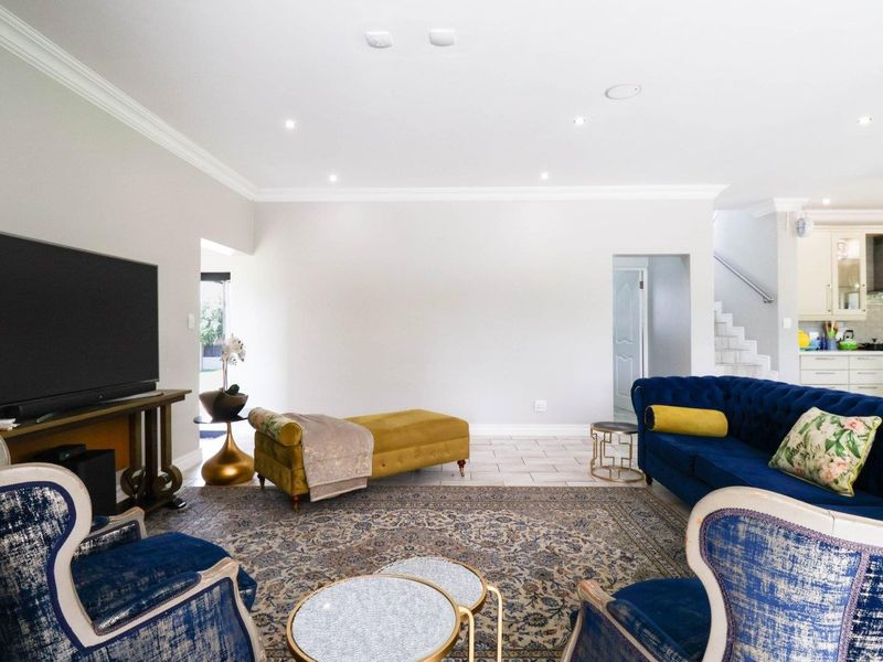 Spacious open-plan living area featuring tiled floors, recessed lighting, and crown molding, with a seamless transition to the adjacent kitchen and staircase.