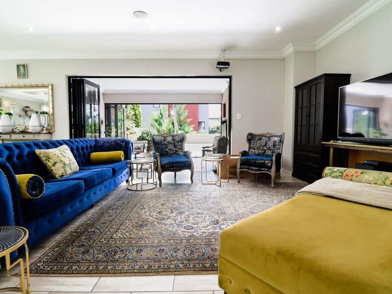 Spacious living room featuring tiled flooring, recessed downlights, and large bi-fold doors that open onto an outdoor patio area.