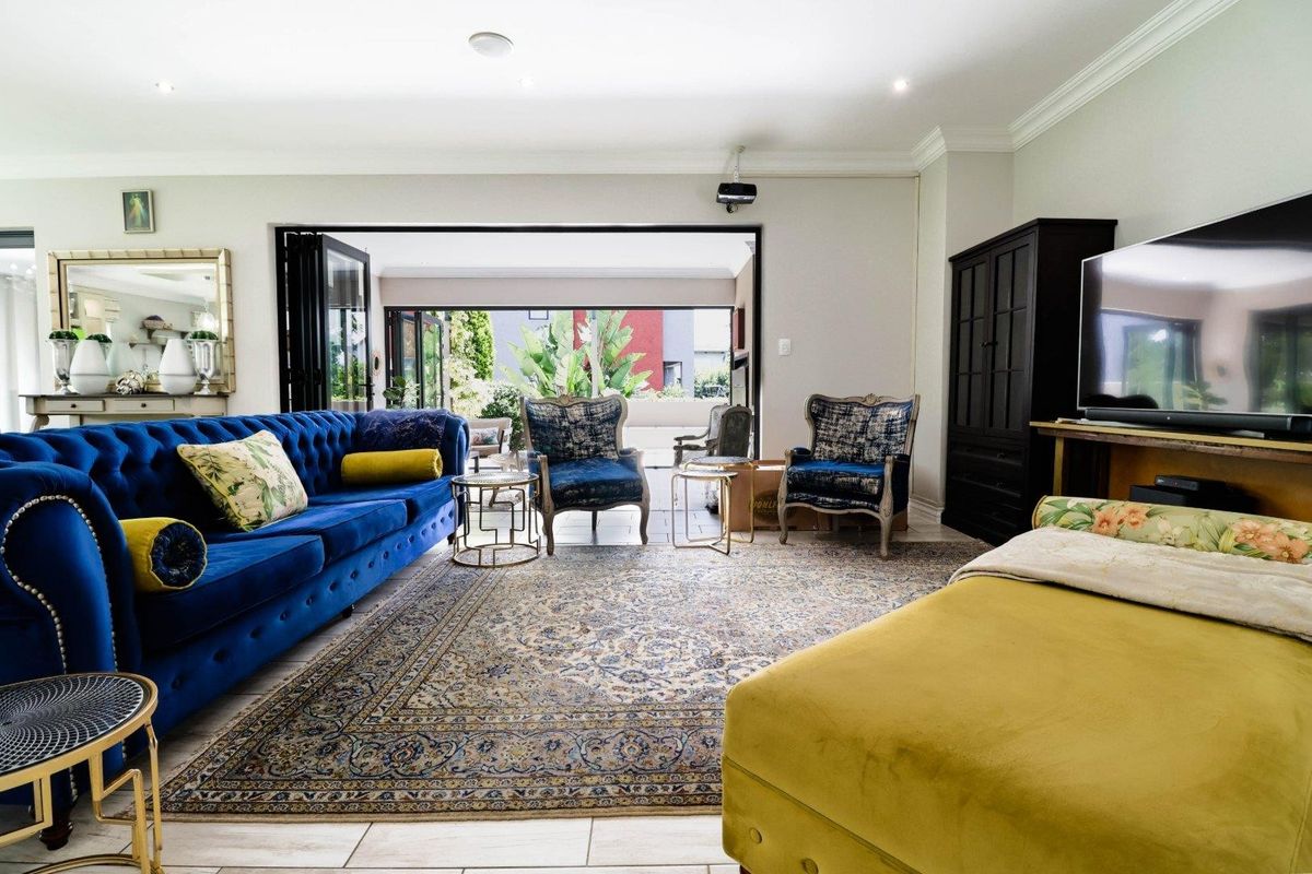 Spacious living room featuring tiled flooring, recessed downlights, and large bi-fold doors that open onto an outdoor patio area.