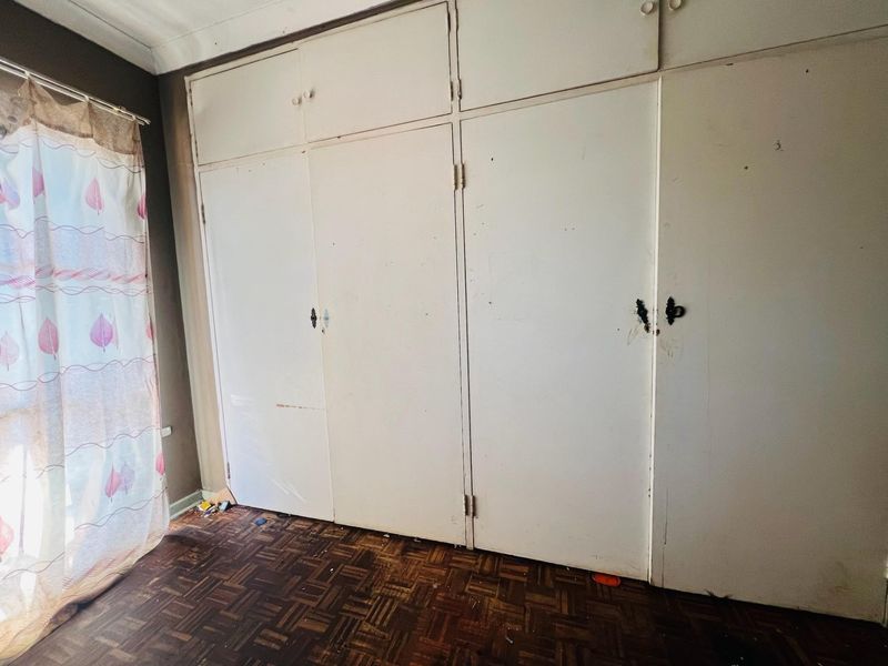 Bedroom featuring original parquet flooring and extensive built-in cupboard storage with overhead cabinetry.