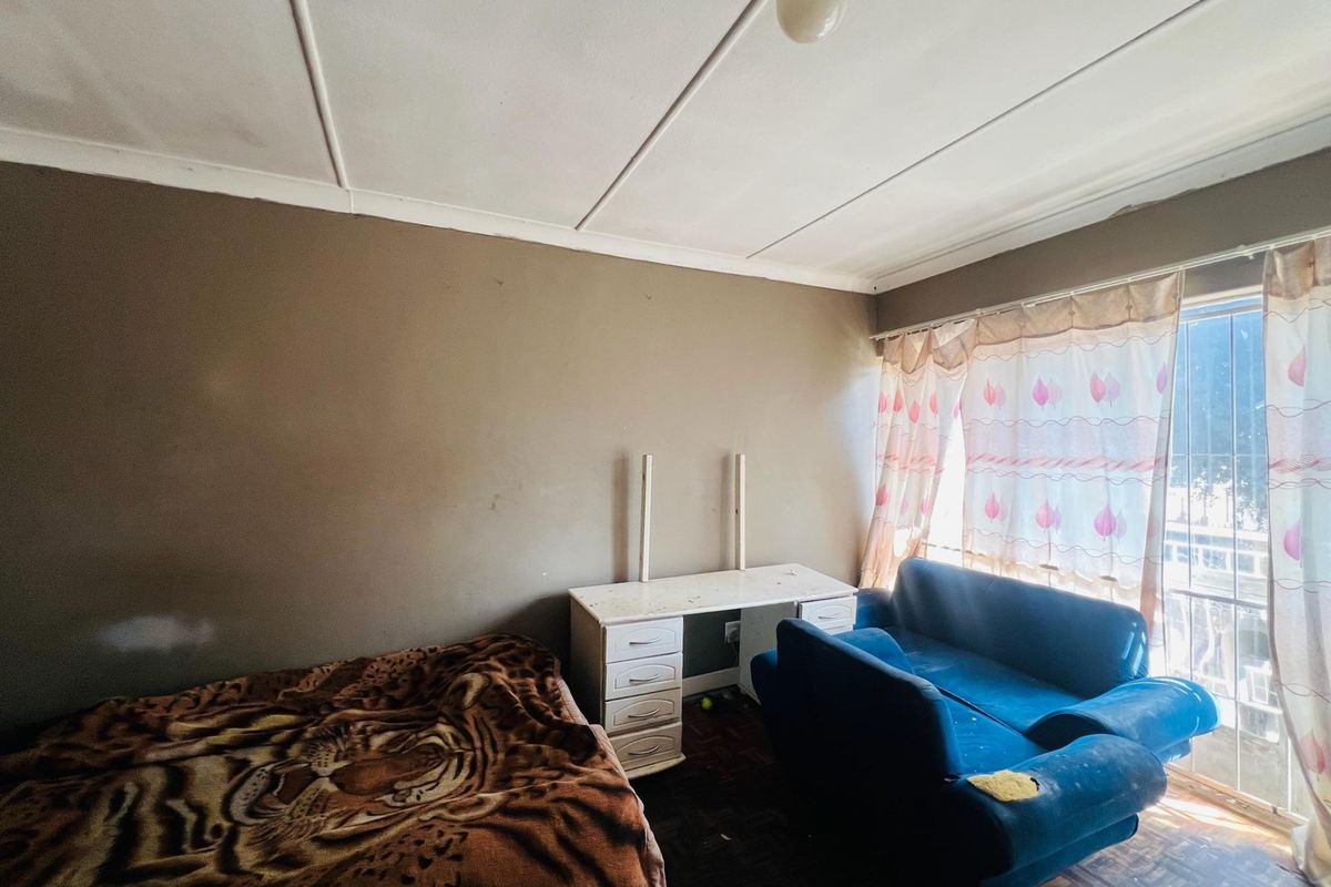A bedroom featuring parquet flooring and ceiling tiles, requiring cosmetic updates to improve the overall condition and appeal of the space.