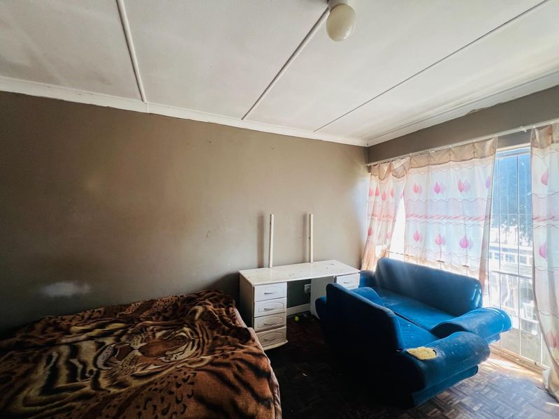 A bedroom featuring parquet flooring and ceiling tiles, requiring cosmetic updates to improve the overall condition and appeal of the space.