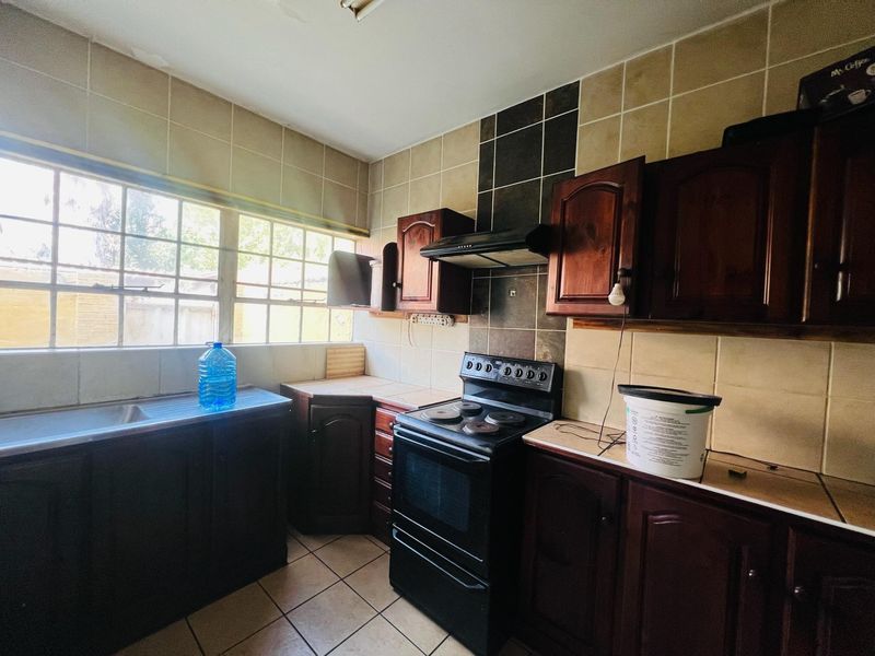 A dated kitchen featuring dark wood cabinetry, tiled backsplash, and a freestanding stove, offering potential for a modern renovation.