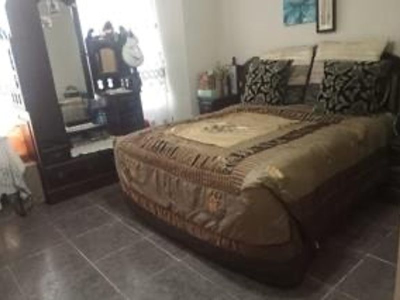 A bedroom featuring tiled flooring and neutral wall finishes, providing a functional space for rest.