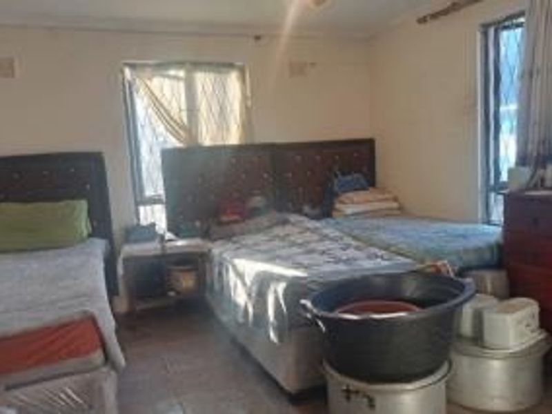 A bedroom featuring tiled flooring and security bars on the windows, currently requiring cosmetic updates to the walls and ceiling.