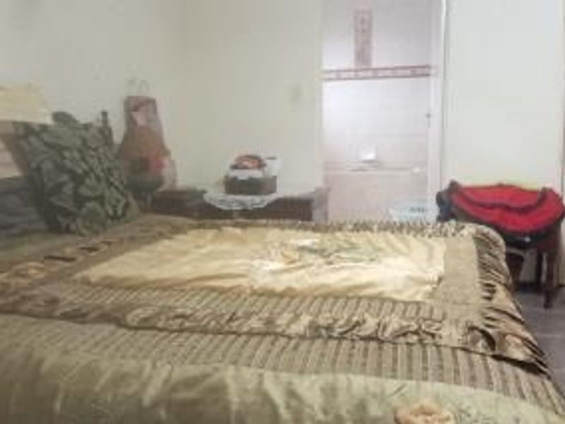 A bedroom featuring tiled flooring and an adjoining en-suite bathroom.