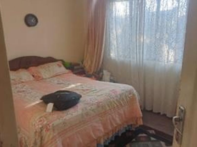 A standard bedroom featuring a window with curtains and a door entrance.