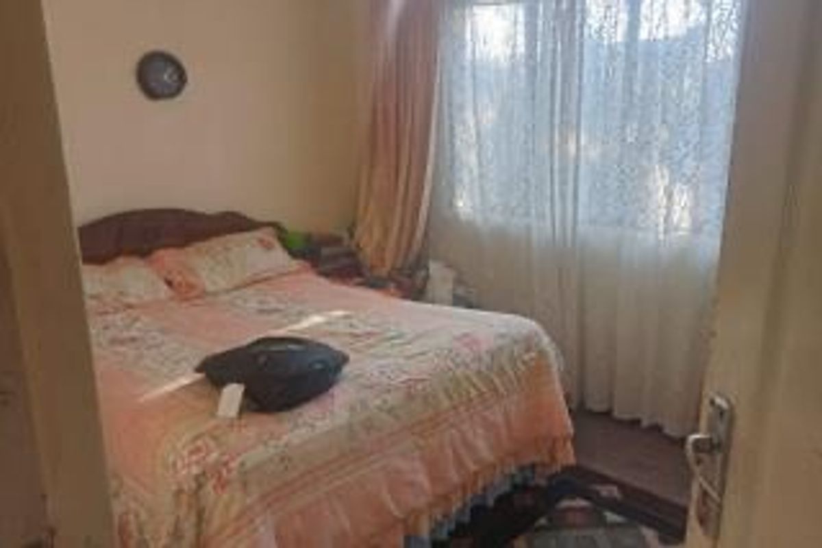 A standard bedroom featuring a window with curtains and a door entrance.