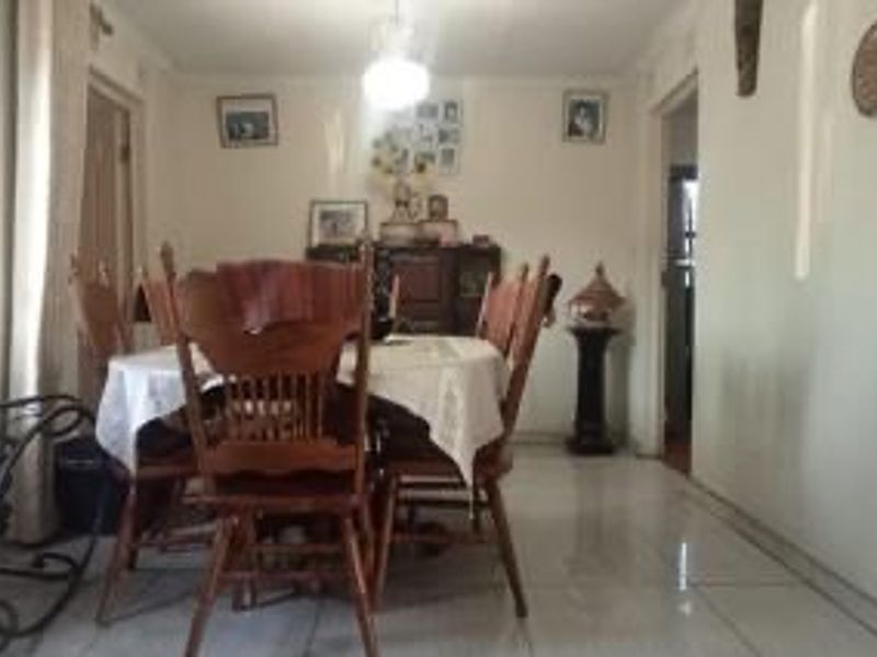 A dining room featuring tiled flooring and a central ceiling light fixture, providing a functional space for family meals.