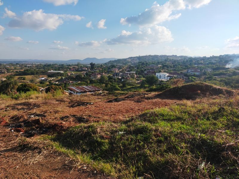 A wide-angle view overlooking a residential neighbourhood from an elevated, undeveloped plot of land.