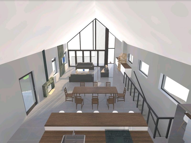 A high-angle view of an open-plan living, dining, and kitchen area featuring a vaulted ceiling, fireplace, and large glass windows.