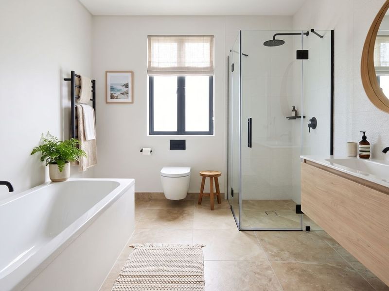 Modern, well-appointed bathroom featuring a floating vanity, walk-in shower, and a sleek freestanding bathtub with contemporary matte black fixtures.