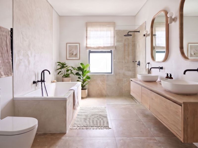Modern, high-end bathroom featuring a double vanity with vessel sinks, a freestanding bathtub, and a spacious walk-in shower with contemporary matte black fixtures.