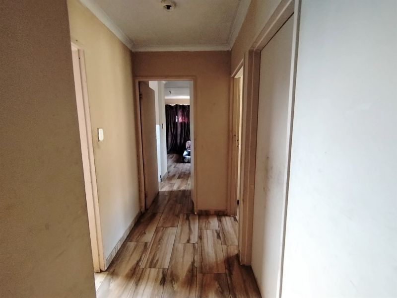 A narrow interior hallway featuring wood-look tile flooring and neutral wall finishes, providing access to multiple rooms within the home.