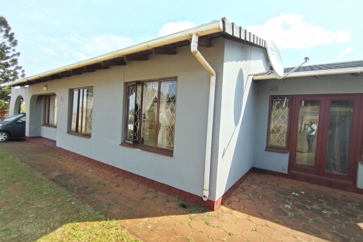 Rear exterior view of the house featuring a paved patio area, security-barred windows, and functional guttering system.