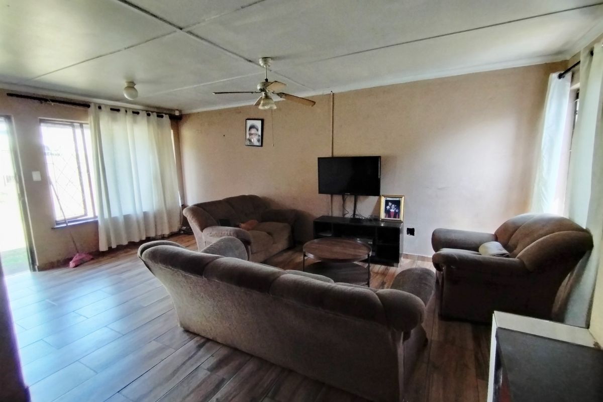 A living room featuring tiled flooring, a ceiling fan, and security bars on the windows, offering a functional space with potential for cosmetic updates.