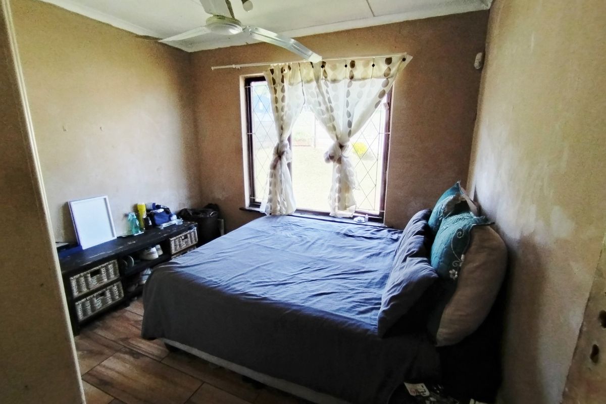 A bedroom featuring tiled flooring, a ceiling fan, and a leaded glass window. The walls require cosmetic attention and refinishing.