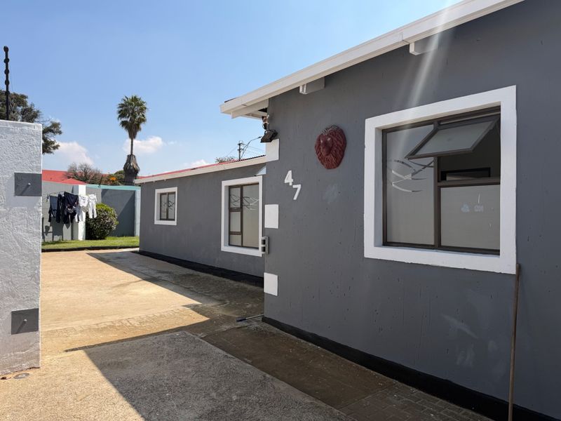 A view of the front exterior of the property featuring grey painted walls, white window frames, and a concrete driveway.